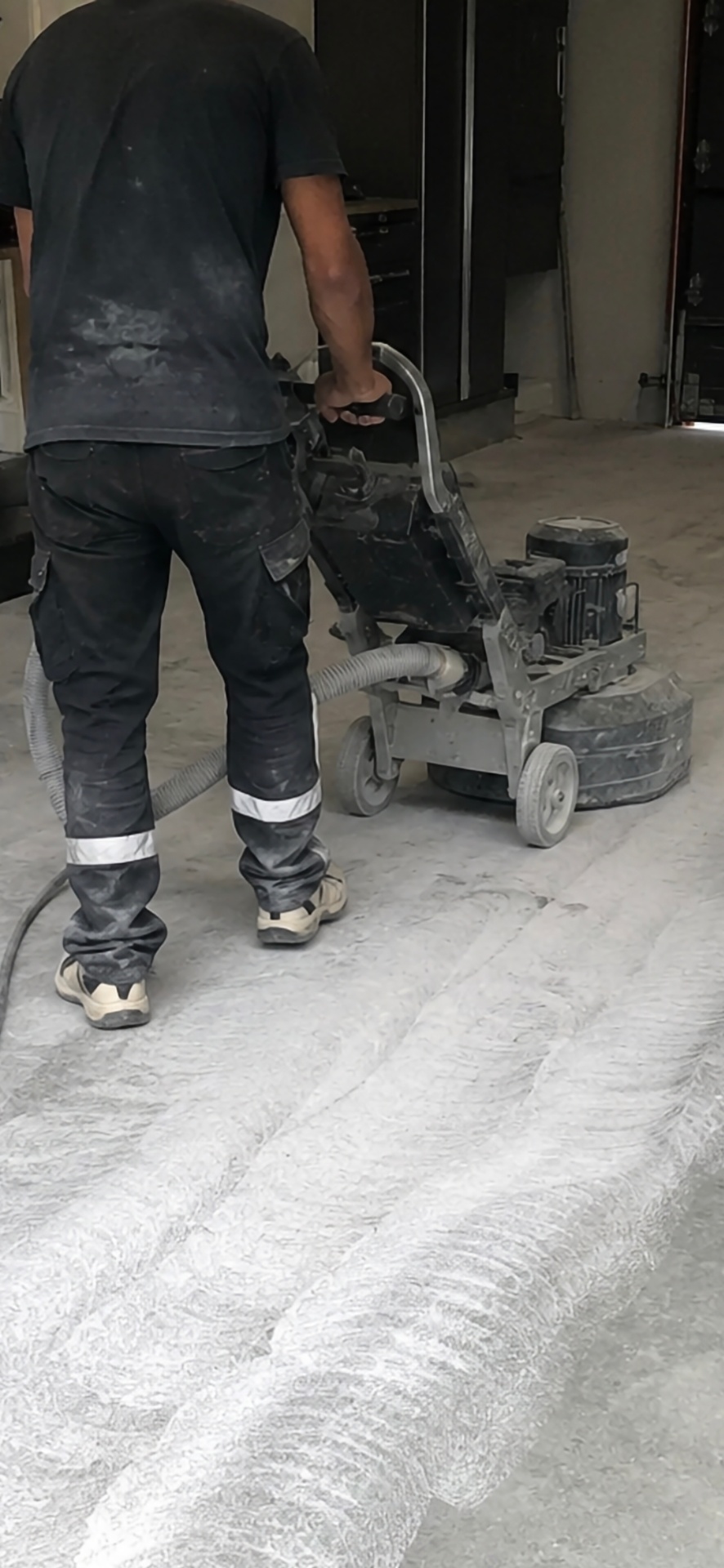 Technician mechanically grinding a concrete floor during preparation